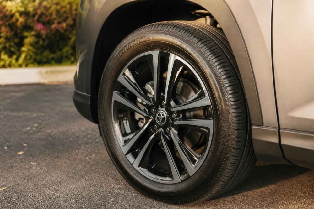 Zbliżenie na czarne aluminiowe koło samochodu Toyota zaparkowanego na podjeździe