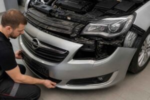 Mechanik dopasowuje przedni zderzak w uszkodzonym samochodzie Opel