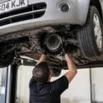 Mechanik sprawdza podwozie samochodu uniesionego na podnośniku warsztatowym