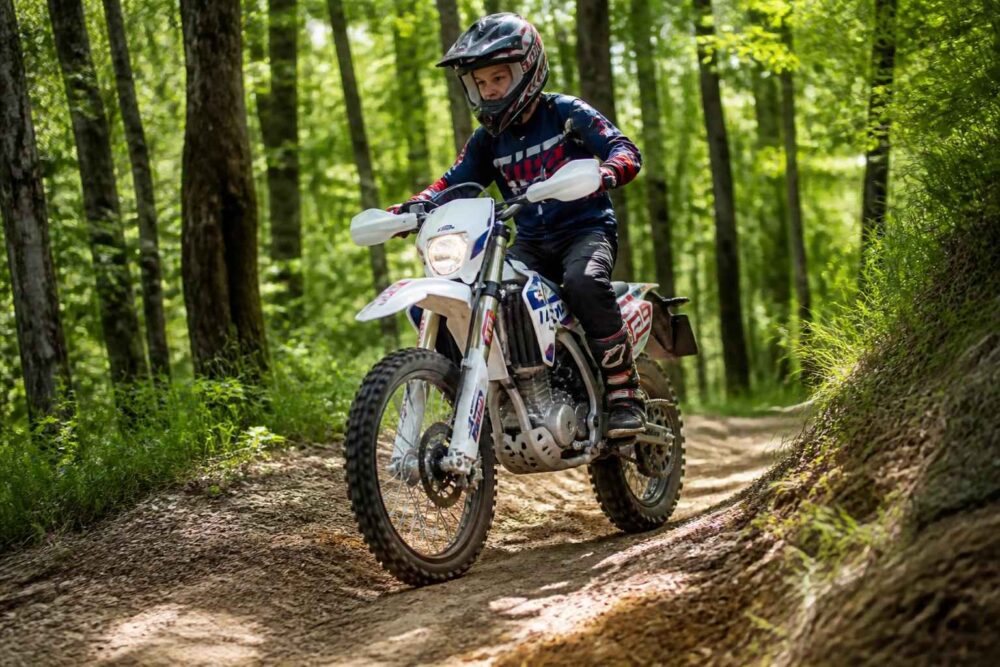 Motocyklista w kasku jedzie terenowym motocyklem przez leśną ścieżkę