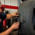 Mechanik naprawia uszkodzenie bieżnika dużej opony samochodowej przy użyciu narzędzia ręcznego