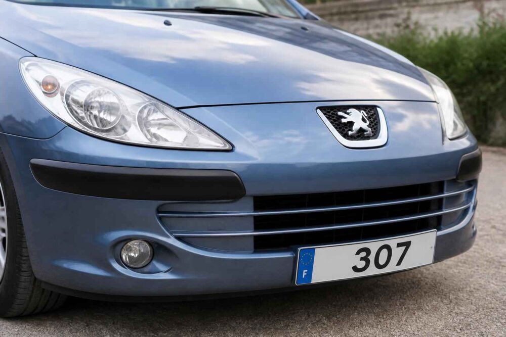 Przód niebieskiego Peugeota 307 z widocznym grillem, reflektorami i tablicą rejestracyjną