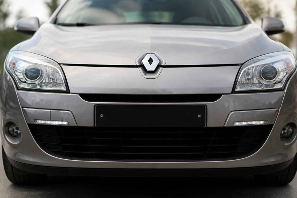 Przód srebrnego Renault Megane z widocznym grillem, reflektorami i logo marki