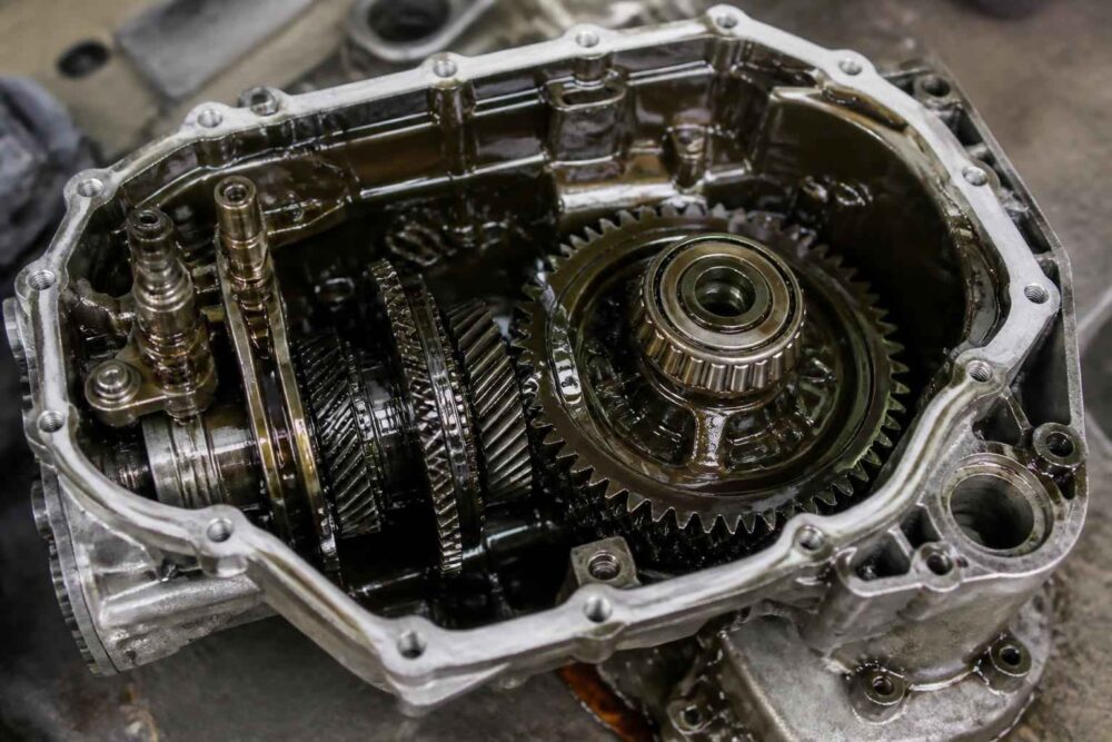 Otwarta skrzynia biegów z widocznymi kołami zębatymi i mechanizmem przekładniowym